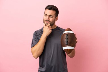 Genç beyaz adam rugby oynuyor. Pembe arka planda izole edilmiş. Yana bakıyor ve gülümsüyor.