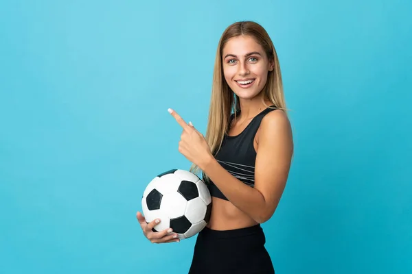 Νεαρή Ξανθιά Γυναίκα Απομονωμένη Μπλε Φόντο Μπάλα Ποδοσφαίρου Και Δείχνοντας — Φωτογραφία Αρχείου