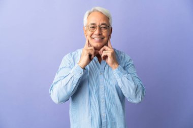 Orta yaşlı Brezilyalı bir adam mor arka planda izole edilmiş mutlu ve hoş bir ifadeyle gülümsüyor.