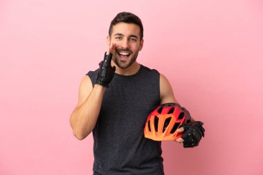 Pembe arka planda izole edilmiş genç bisikletçi ağzı açık bağırıyor.
