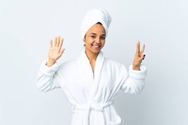 Bornozlu genç kadın izole edilmiş beyaz arka planda sekiz parmaklı sayıyor.