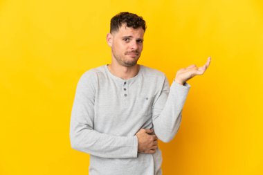 Sarı arka planda izole edilmiş beyaz, yakışıklı bir genç. Şüpheleri var.