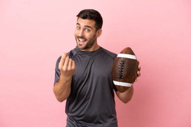 Genç beyaz adam rugby oynuyor. Pembe arka planda izole edilmiş. Para hareketi yapıyor.