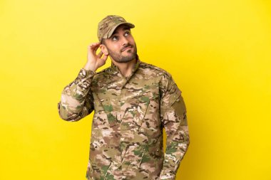 Asker sarı arka planda izole edilmiş bir fikir düşünüyor.