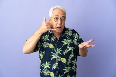 Mor arka planda izole edilmiş orta yaşlı Brezilyalı bir adam telefon jesti yapıyor ve şüpheli.