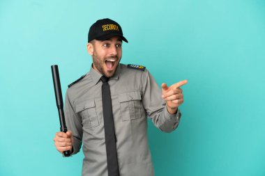Mavi arka planda izole edilmiş genç bir güvenlik elemanı parmağını yana doğru uzattı ve bir ürün sundu.