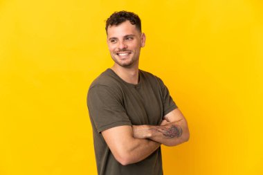 Sarı arka planda izole edilmiş beyaz, yakışıklı genç adam yana bakıyor ve gülümsüyor.