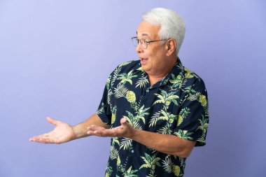 Orta yaşlı Brezilyalı bir adam, mor arka planda yalıtılmış, sürpriz bir ifadeyle yan tarafa bakıyor.