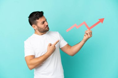 Mavi arka planda izole edilmiş yakışıklı beyaz bir adam yükselen bir oku tutuyor ve ona doğrultuyor.