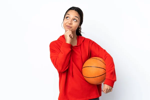 若いです女性遊ぶバスケットボール上の隔離された白い背景考えながら考えを見上げます — ストック写真