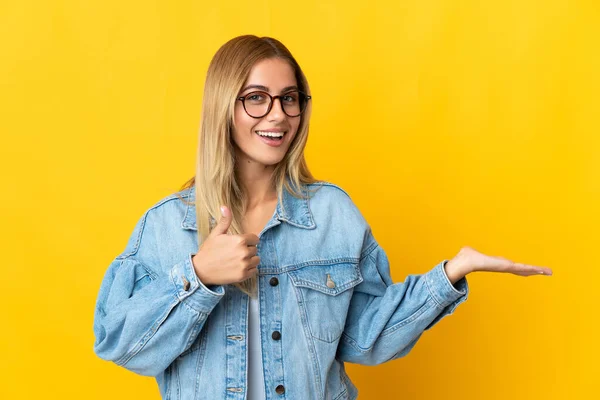 Mujer Rubia Joven Aislada Sobre Fondo Amarillo Sosteniendo Espacio Copia — Foto de Stock