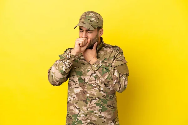 Military man isolated on yellow background is suffering with cough and feeling bad