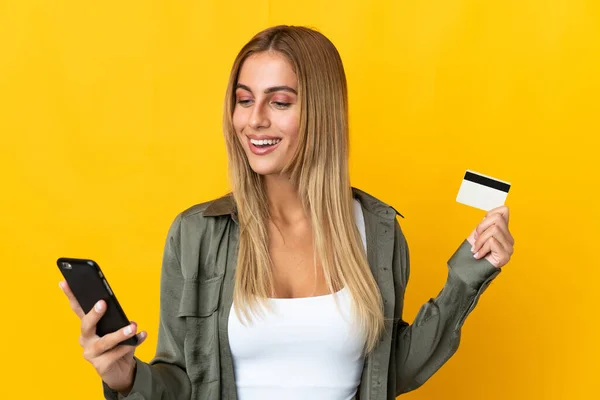 Mladé Blondýny Žena Izolované Žlutém Pozadí Nákup Mobilem Kreditní Kartou — Stock fotografie