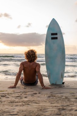 Kafkasyalı genç adam gün doğumunda sörf yapmak için erken kalkar.