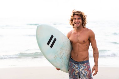 Kafkasyalı genç adam gün doğumunda sörf yapmak için erken kalkar.