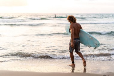 Kafkasyalı genç adam gün doğumunda sörf yapmak için erken kalkar.