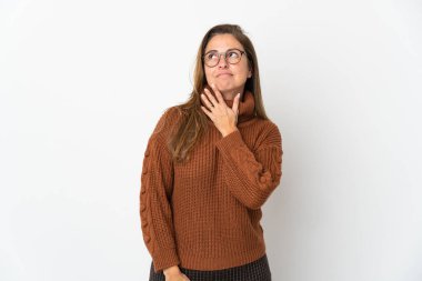 Orta yaşlı Brezilyalı kadın beyaz arka planda izole edilmiş gülümserken yukarı bakıyor