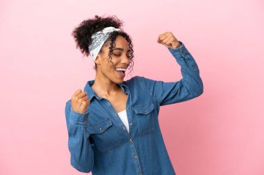 Pembe arka planda izole edilmiş genç Latin kadın zaferi kutluyor.