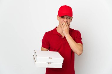 İş üniformalı bir pizzacı beyaz arka planda izole edilmiş pizza kutularını topluyor mutlu ve gülümseyen ağızlarını eliyle kapatıyor.