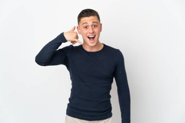 Beyaz arka planda izole edilmiş genç beyaz bir adam telefon jesti yapıyor. Bana geri dönüş işareti ver.