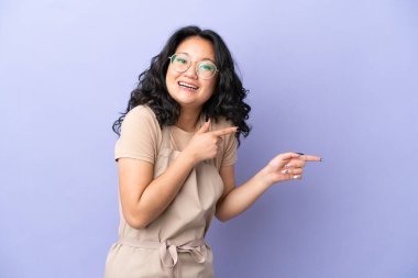 Mor arka planda izole edilmiş Asyalı garson şaşırmış ve işaret ediyor.