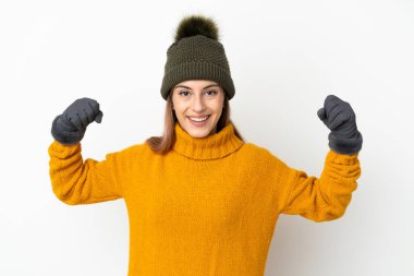 Beyaz arka planda izole edilmiş, kış şapkalı genç kız güçlü bir jest yapıyor.