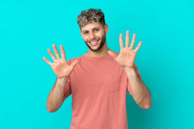 Mavi arka planda izole edilmiş yakışıklı beyaz adam parmaklarıyla ona kadar sayıyor.