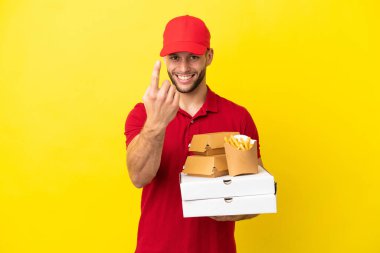 Pizza teslimatçısı, izole edilmiş arka planda pizza kutuları ve burgerleri alıyor.