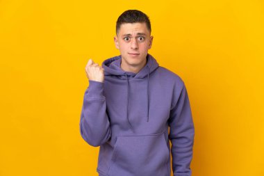 Mutsuz bir ifadeyle sarı arka planda izole edilmiş genç beyaz bir adam.