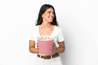 Beyaz arka planda izole edilmiş beyaz bir kadın elinde koca bir kova patlamış mısır tutuyor.