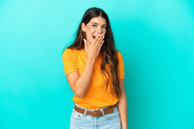 Mavi arka planda izole edilmiş genç beyaz kadın mutlu ve gülümsüyor.