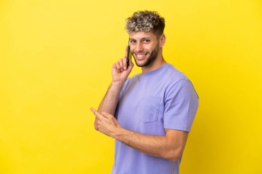 Sarı arka planda izole edilmiş cep telefonu kullanan beyaz bir adam.