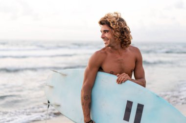 Kafkasyalı genç adam gün doğumunda sörf yapmak için erken kalkar.