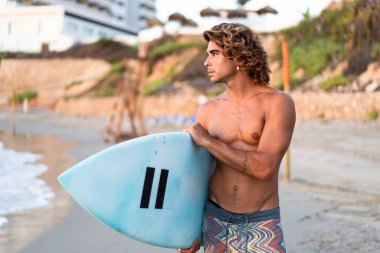 Kafkasyalı genç adam gün doğumunda sörf yapmak için erken kalkar.