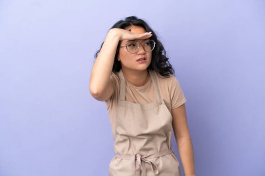 Restoran Asyalı garson, mor arka planda izole edilmiş. Bir şeye bakmak için çok uzaklara bakıyor.