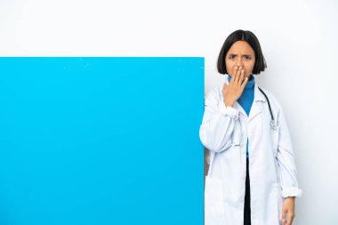 Beyaz arka planda izole edilmiş, ağzı eliyle kapatılmış büyük bir afişi olan genç ırk doktoru kadın.