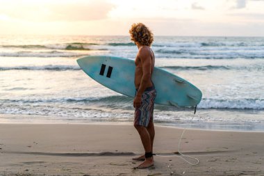 Kafkasyalı genç adam gün doğumunda sörf yapmak için erken kalkar.