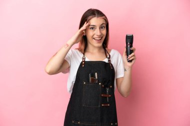 Genç kuaför kadın pembe arka planda izole edilmiş, sürpriz bir ifadeyle.