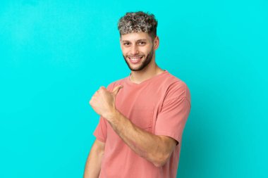 Mavi arka planda soyutlanmış yakışıklı beyaz adam gururlu ve kendini beğenmiş.