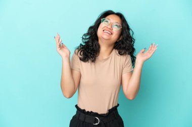 Asyalı genç bir kadın mavi arka planda izole edilmiş, çok gülümsüyor.