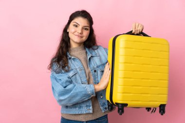 İzole edilmiş pembe arka planda bavulu olan bir gezgin.