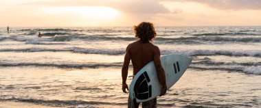 Kafkasyalı genç adam gün doğumunda sörf yapmak için erken kalkar.