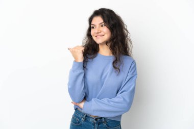 Beyaz arka planda izole edilmiş genç Rus kız bir ürünü sunmak için kenarı işaret ediyor.