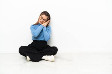 Genç, beyaz bir kadın yerde oturmuş, hareketli bir uyku hareketi yapıyor.