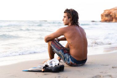 Genç beyaz adam denize dalmaya hazırlanıyor.