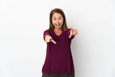 Beyaz arka planda izole edilmiş orta yaşlı Brezilyalı kadın şaşırmış ve ön tarafı işaret ediyor.