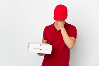 İş üniformalı bir pizzacı beyaz arka planda izole edilmiş, yorgun ve hasta bir ifadeyle pizza kutuları alıyor.