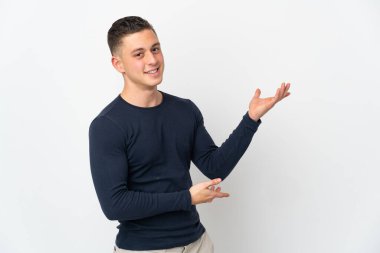 Beyaz arka planda soyutlanmış beyaz tenli genç adam davet edilmek için ellerini yana uzatıyor.