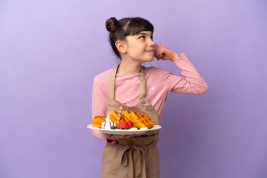 Mor arka planda gözleme tutan küçük beyaz kız şüpheleri var ve düşünüyor.