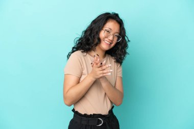 Genç Asyalı bir kadın mavi arka planda izole edilmiş bir konferansta sunumdan sonra alkışlıyor.